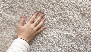 This image shows a hand pressing against a carpet.