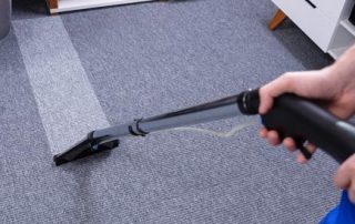 This image shows a man using a vacuum to clean a carpet