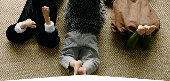 This image shows kids laying on the carpet with their feet up.