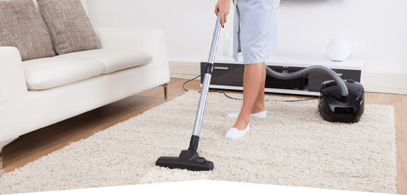 This image shows a woman using a vacuum to clean a carpet